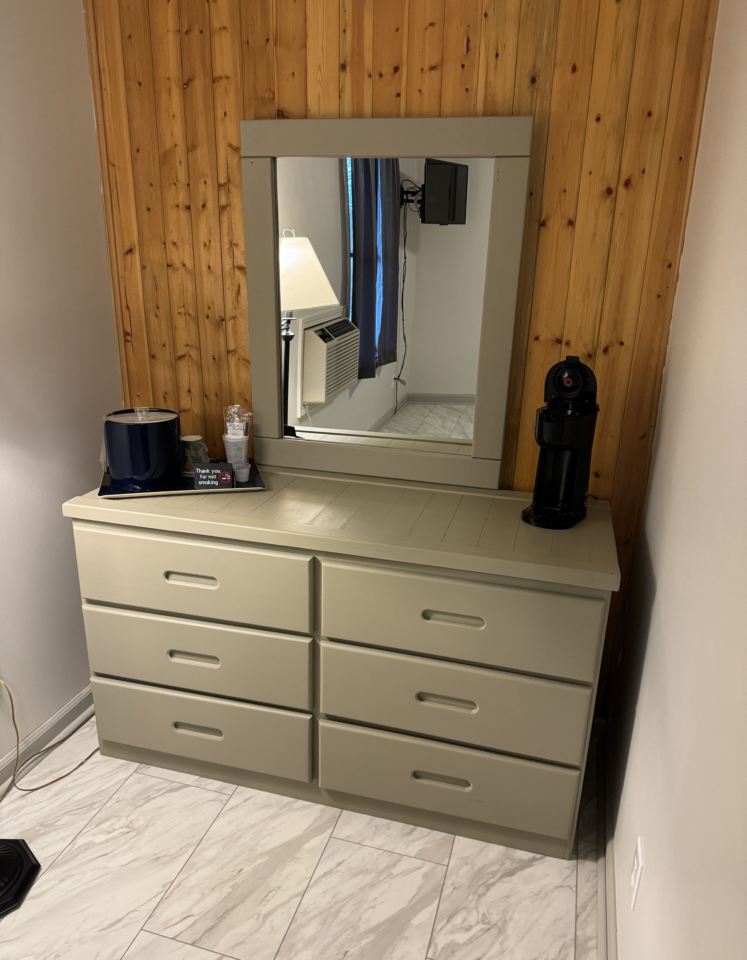 A bathroom with a wooden panel wall, a mirror, a sink, and a shower.