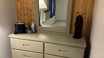 A bathroom with a wooden panel wall, a mirror, a sink, and a shower.