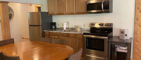 Una cocina moderna con armarios de madera, electrodomésticos de acero inoxidable y una mesa redonda con sillas.