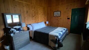 A bedroom with a bed, dresser, and a green door.