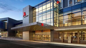 A modern Marriott hotel with a glass facade, a prominent logo, and a clear departure sign.