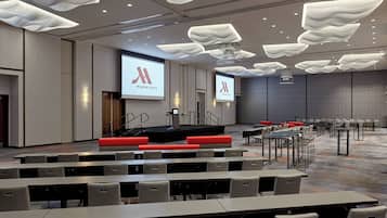 A conference room with a stage, seating, and a large screen displaying the Marriott logo.