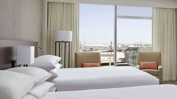 A hotel room with two beds, a view of the city, and a large window.
