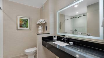 A modern bathroom with a black countertop, a large mirror, a toilet, and a towel rack.