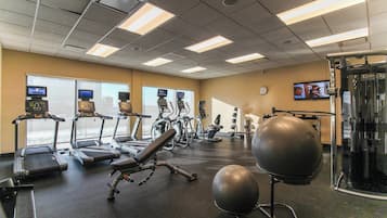 Un gimnasio con cintas de correr, elípticas, una bicicleta estática y máquinas de pesas.