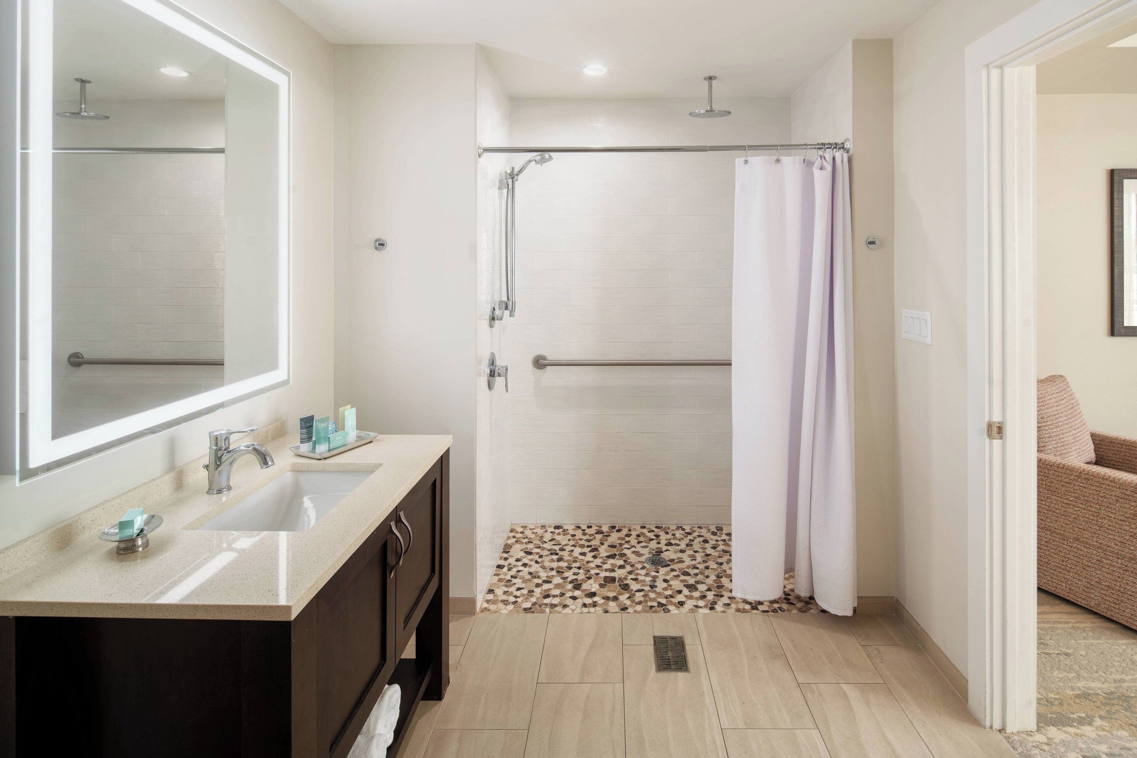 A modern bathroom with a shower, a sink, and a mirror.