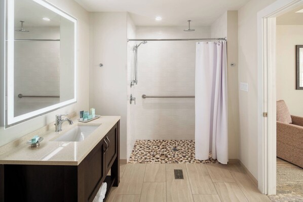 A modern bathroom with a shower, a sink, and a mirror.