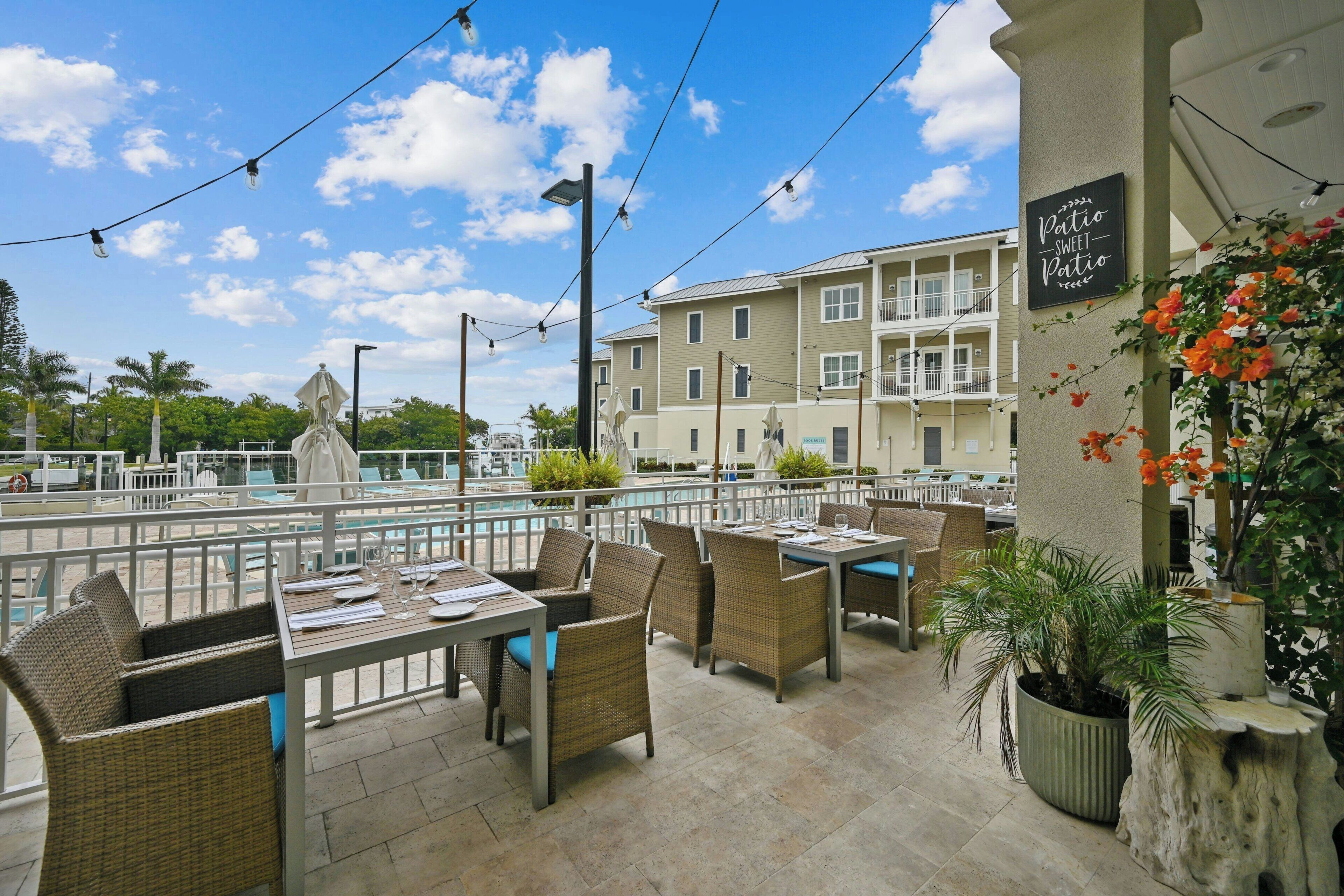 An outdoor patio area with wicker furniture, a pool, and a building with balconies.