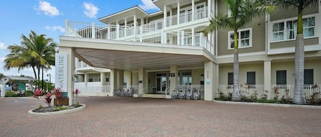 A hotel entrance with a covered walkway, palm trees, and bicycles parked outside.