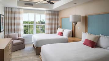 Habitación de hotel con dos camas, una silla, una cómoda, un ventilador de techo y una ventana con cortinas.