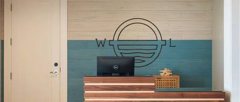 A reception desk with a wooden finish and a laptop on it.