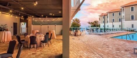 A rooftop terrace with a pool, tables, and chairs, and a view of buildings in the background.