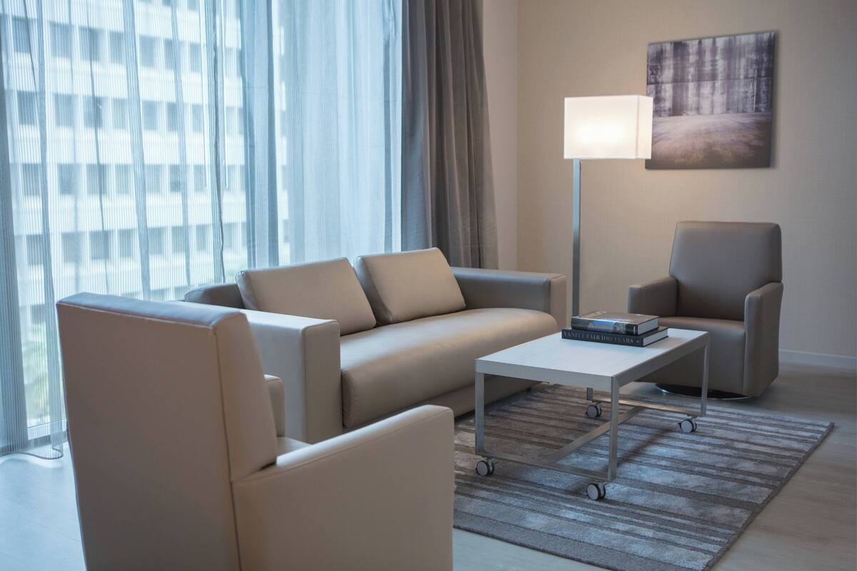 Un salon moderne avec un canapé, des fauteuils, une table basse et une lampe.
