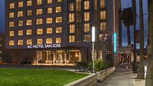 A hotel with a modern facade, a well-lit entrance, and a visible lounge area.