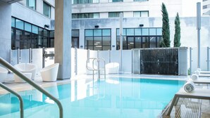 A modern indoor pool area with clear glass walls, a pool, and lounge chairs.