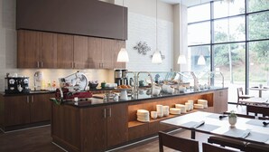 Eine moderne Küche mit Holzschränken, einer zentralen Kochinsel mit Spüle und einem Essbereich mit Tisch und Stühlen.