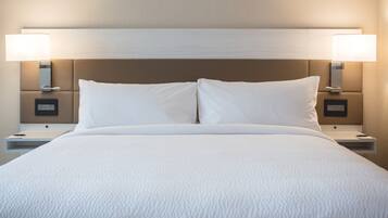 A neatly made bed with white linens, two bedside lamps, and a modern headboard.