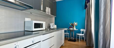 A modern kitchen with a microwave, toaster, and cabinets. There is a dining area with a table and chairs.