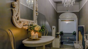 Un baño con un lavabo redondo, un espejo con marco decorativo, dos velas y un florero con flores.
