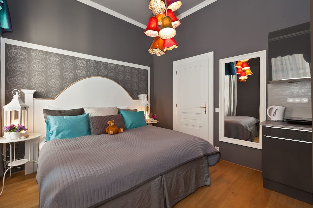 Een slaapkamer met een groot bed, een nachtkastje met een lamp, een kaptafel en een spiegel.