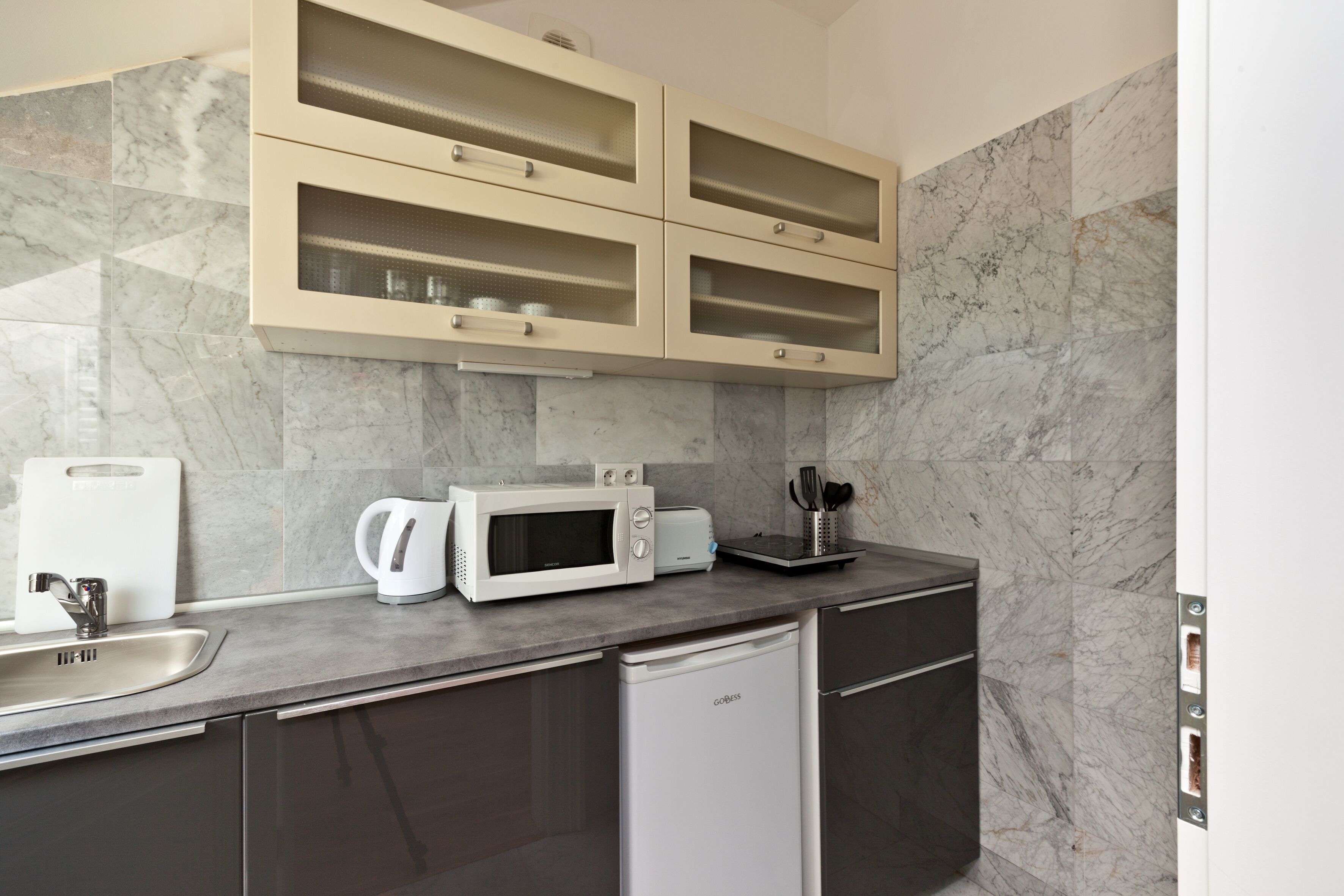 A modern kitchen with a built-in microwave, toaster, and coffee maker on the countertop.
