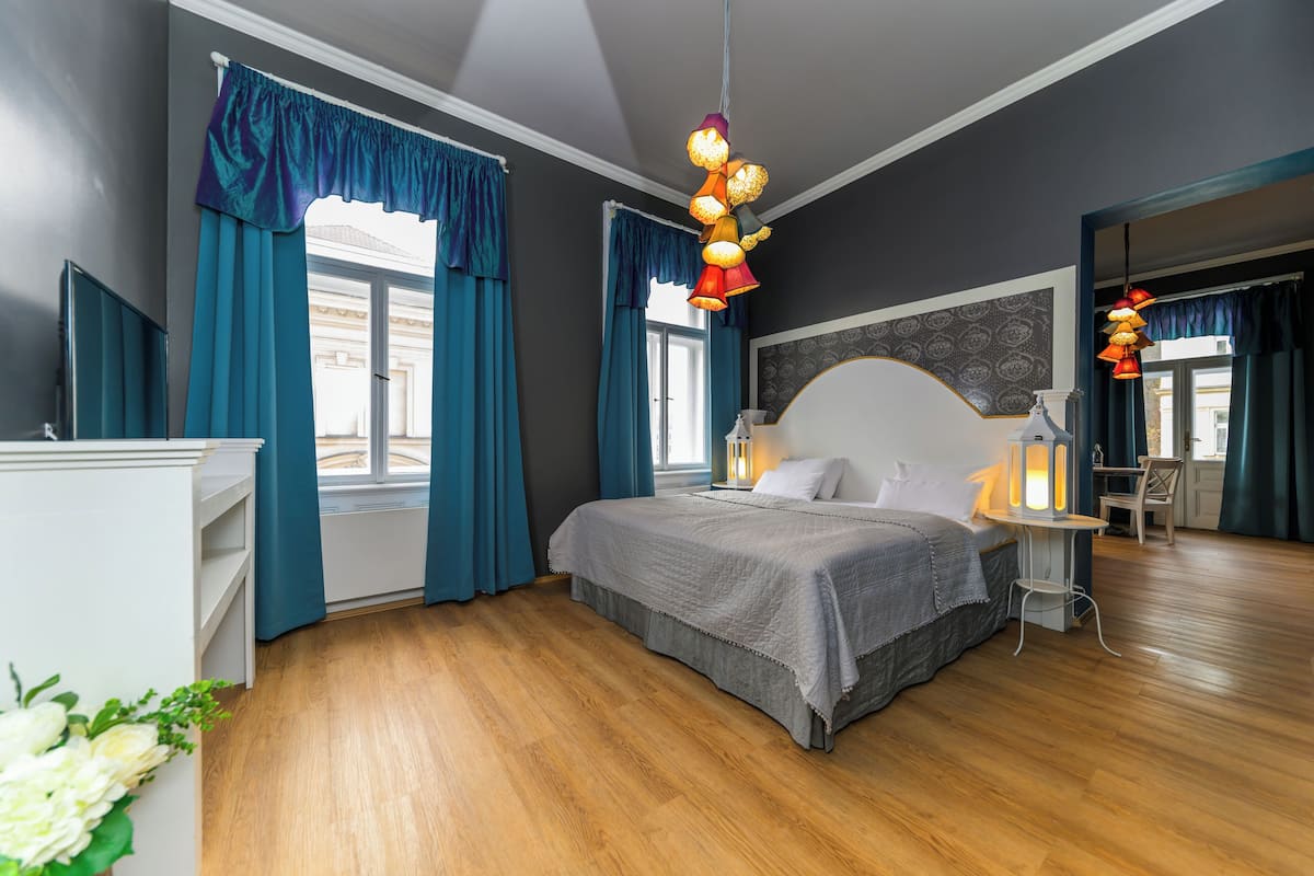 Een moderne slaapkamer met een groot bed, een nachtkastje en een raam met gordijnen.