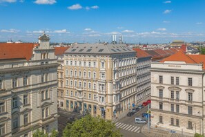 A multi-story building with classical architecture, featuring a central courtyard and a street view with parked cars. - Royal Prague City Apartments (Prague)
