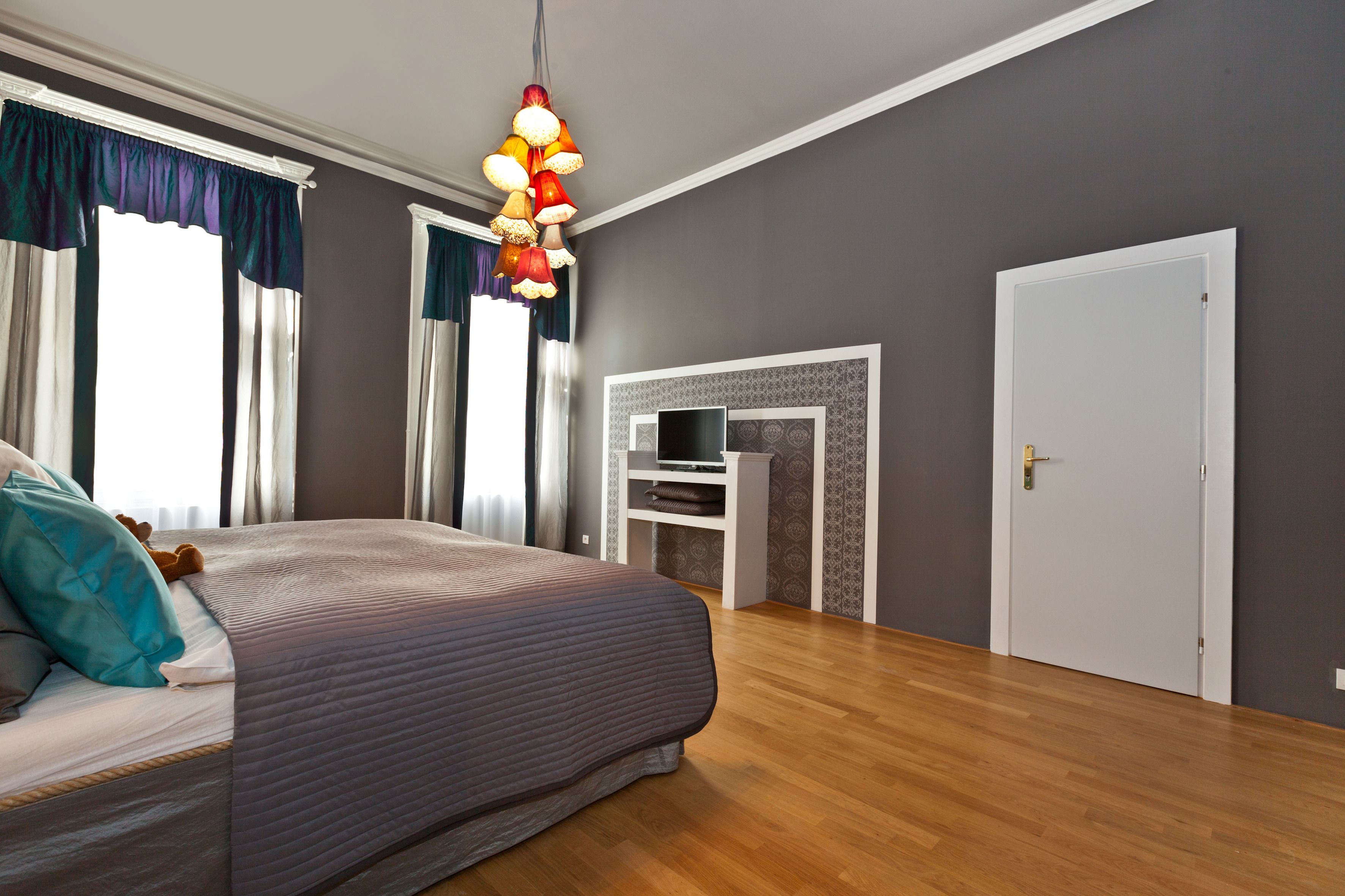 A bedroom with a large bed, a TV stand, and a door.