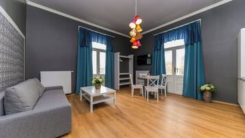 A modern living room with a grey sofa, white coffee table, and blue curtains.