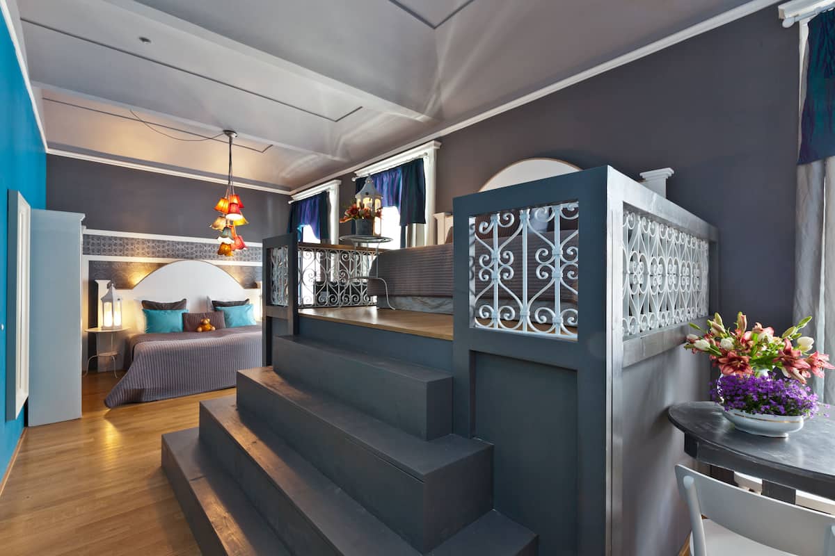 Een moderne hotelkamer met een bed, een bureau en een trap.