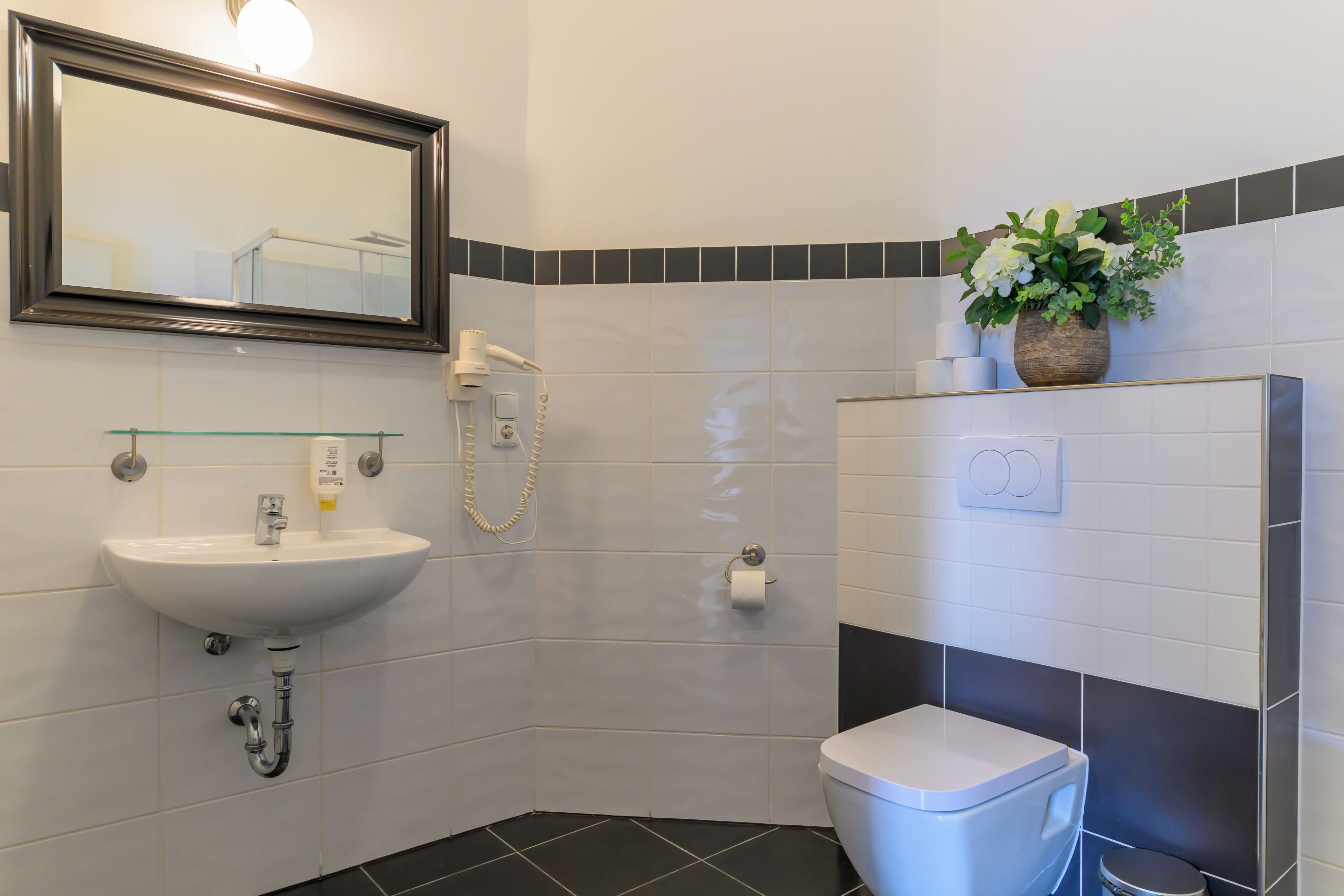 A modern bathroom with a white sink, a toilet, and a shower.