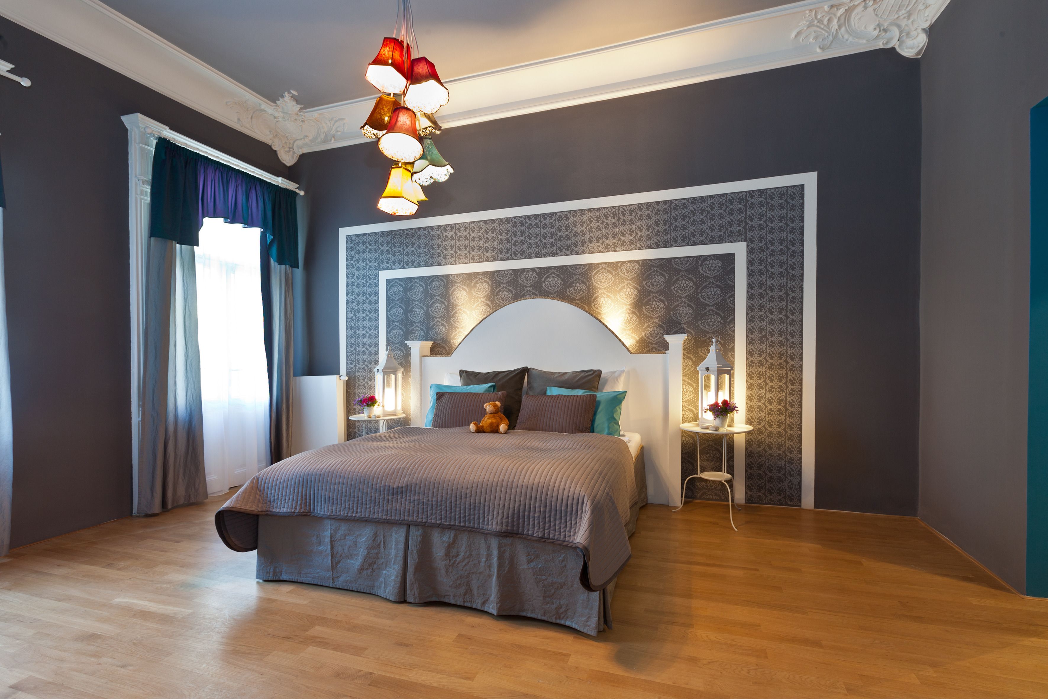 Une chambre moderne avec un grand lit, un luminaire décoratif au plafond et un mur orné d’un motif.