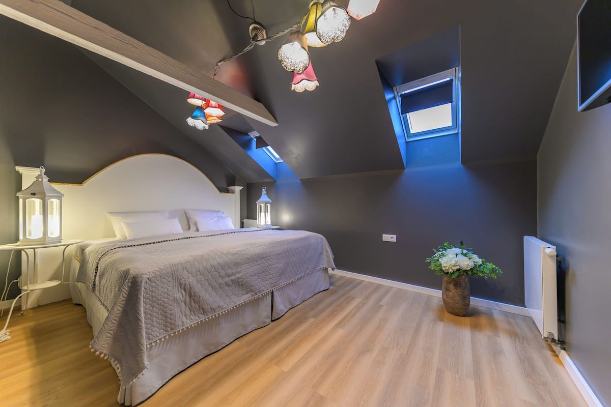 Een slaapkamer met een bed, bedlampen, een nachtkastje, een raam en een radiator.