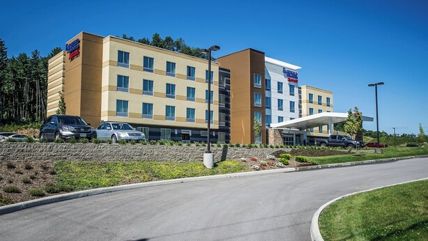 A modern hotel with a flat roof, multiple windows, and a parking area.