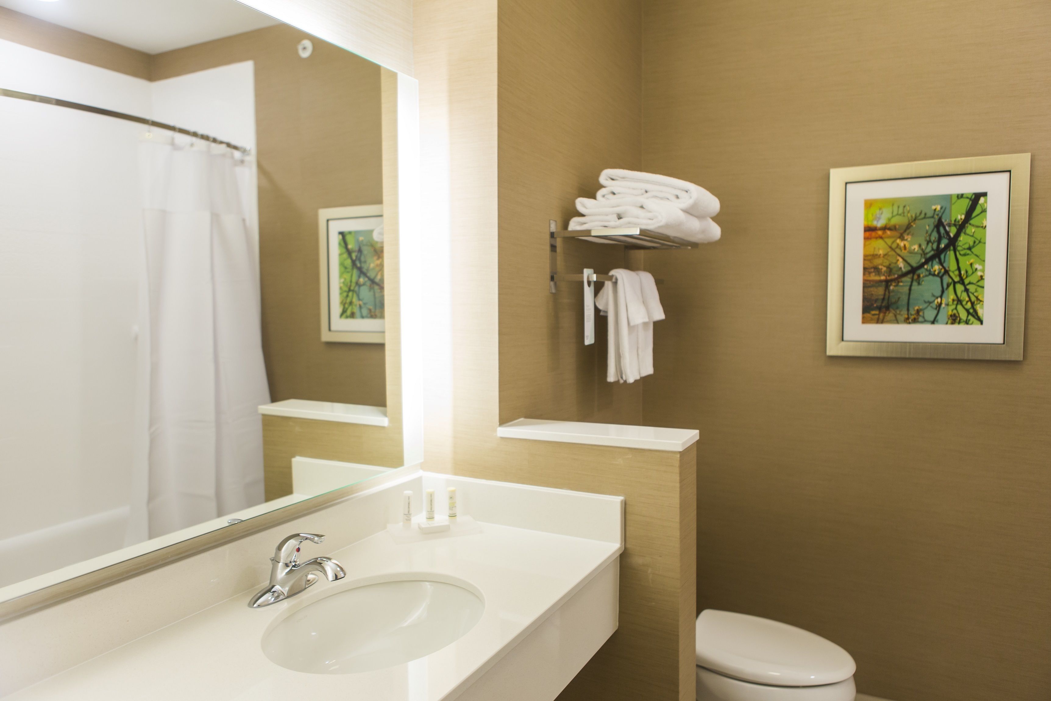 A bathroom with a white sink, a mirror, a toilet, and a towel rack.