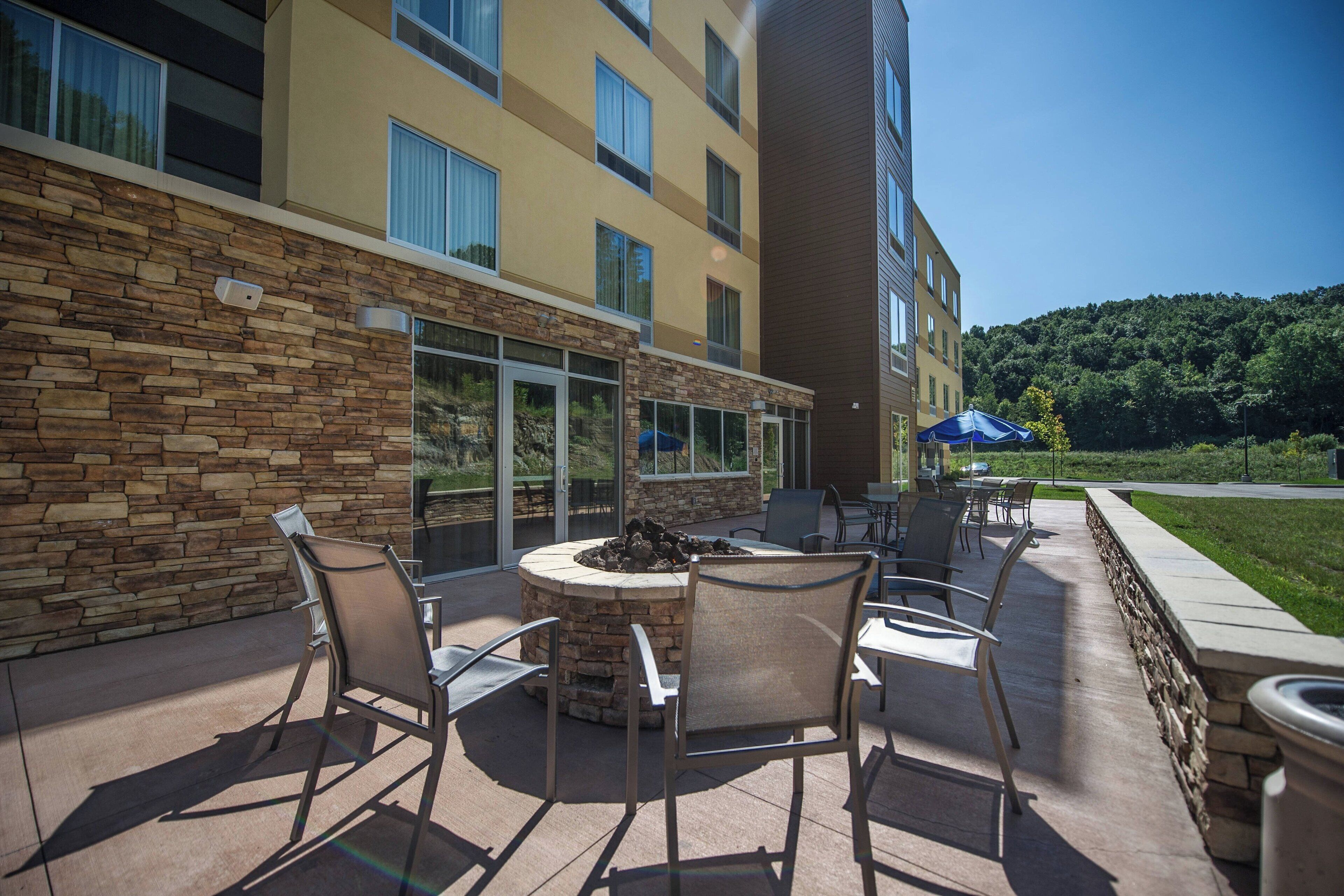 An outdoor patio with stone walls, a fire pit, and outdoor seating.