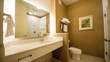 A bathroom with a large mirror, a sink, a toilet, and a towel rack.