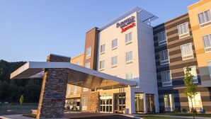 A modern hotel with a clear entrance, a covered waiting area, and a sign indicating a 12-foot clearance.