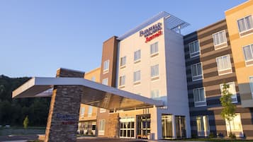 A modern hotel with a clear entrance, a covered waiting area, and a sign indicating a 12-foot clearance.