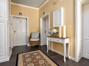 A hallway with a wooden console table, a wicker chair, and a floral arrangement. - Caroline Old Town Square Hotel (Prague)