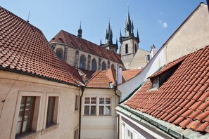 Uma rua estreita com edifícios com telhados vermelhos e uma igreja com várias torres ao fundo.