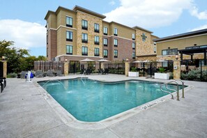 Un hôtel doté d’une piscine, d’un espace extérieur aménagé et d’une façade en briques.