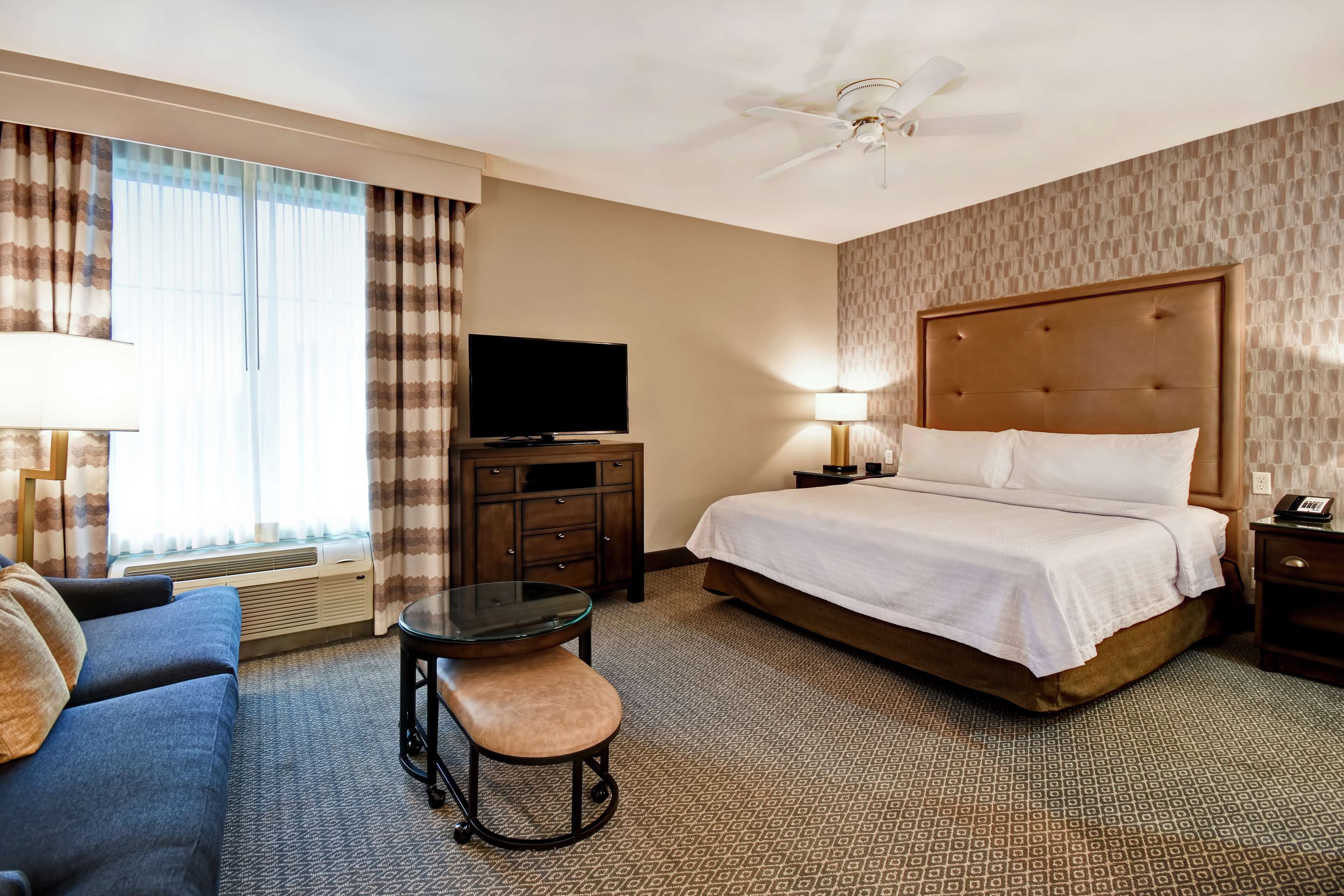 Ein Hotelzimmer mit Bett, Fernseher, Schreibtisch mit Stuhl und Sofa.