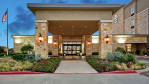 A hotel entrance with a stone facade, a flag, and a sign indicating it is a homewood suites hotel. - Homewood Suites by Hilton Dallas Arlington South (Arlington)