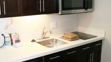 A kitchen with dark cabinets, a stainless steel dishwasher, a microwave, and a sink.