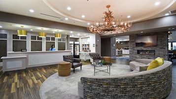 A modern hotel lobby with a curved seating area, a fireplace, and a reception desk.