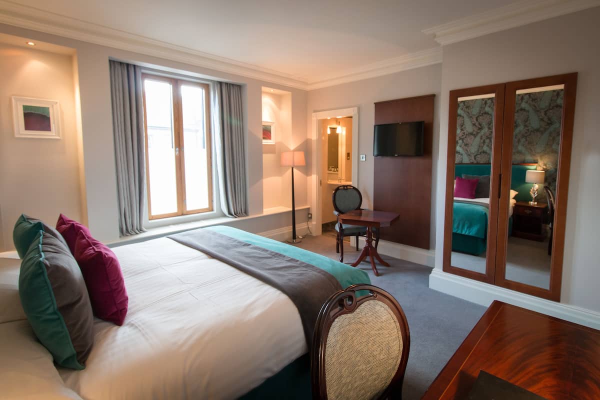 Ein Hotelzimmer mit einem Bett, einem Schreibtisch, einem Stuhl, einem Fernseher und einem Kleiderschrank.