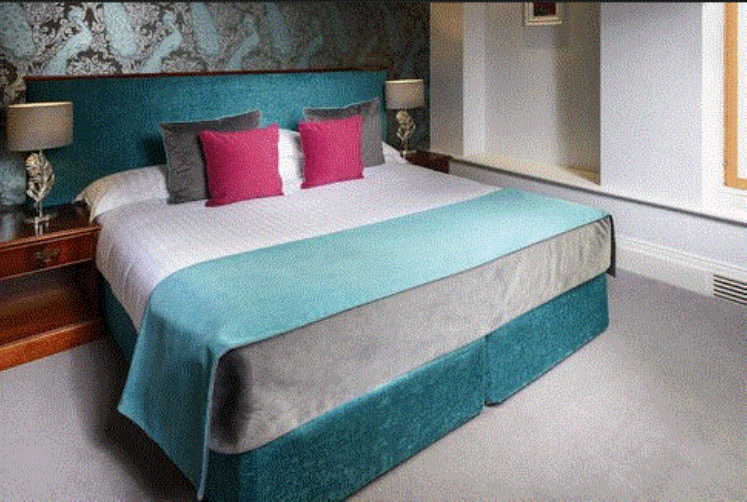 A bedroom with a large bed, two bedside tables, a nightstand, and a window.