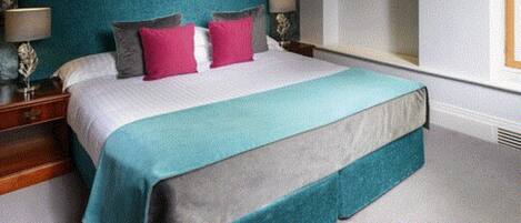 A bedroom with a large bed, two bedside tables, a nightstand, and a window.