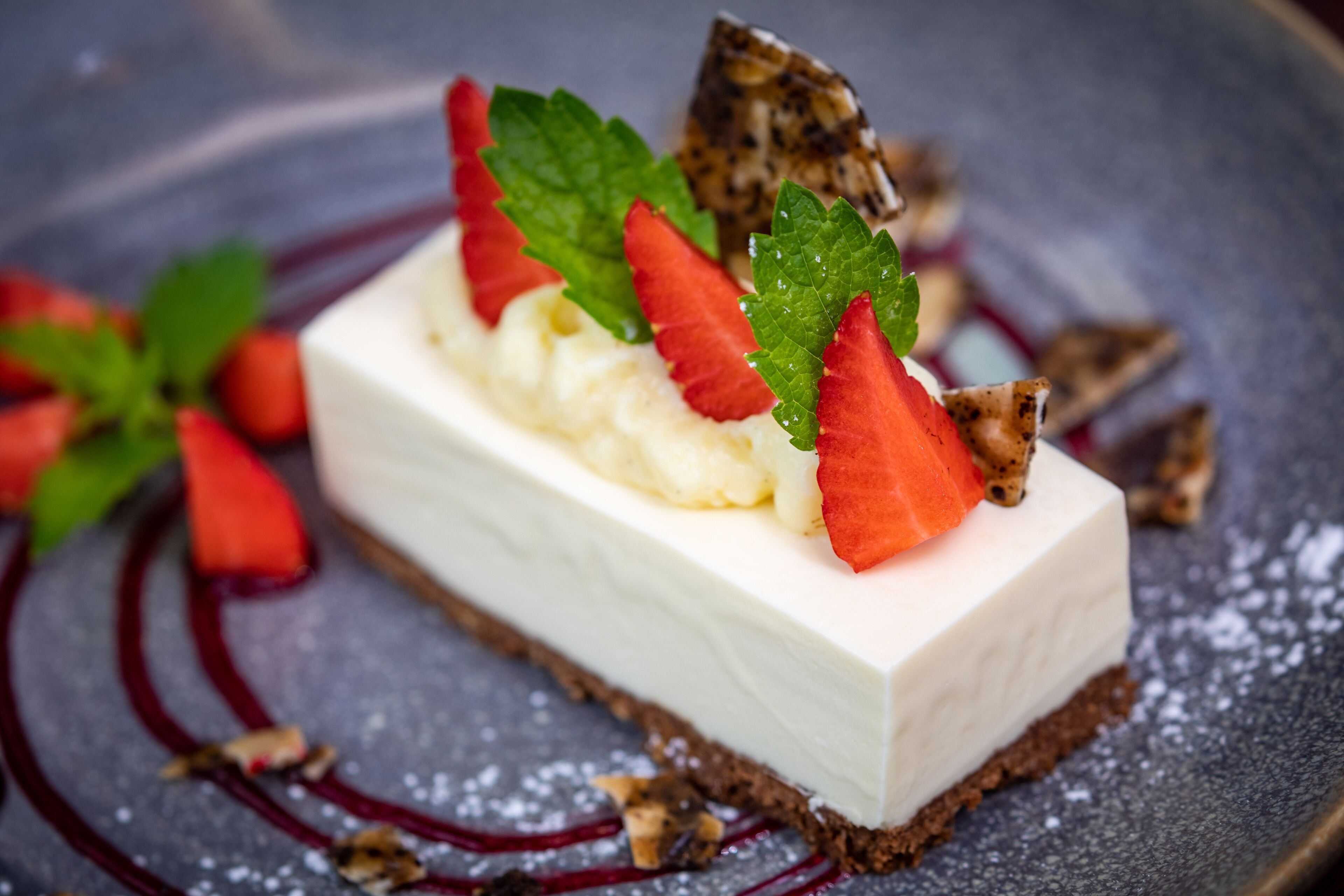 A dessert with strawberries and mint leaves on a plate.
